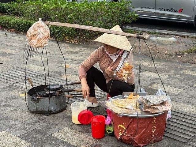 Una vendedora ambulante con su carga al hombro y sombrero cónico tradicional